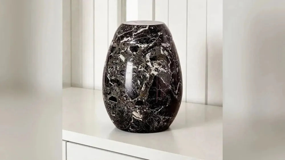 Marble adult cremation urn in black and grey in a living room