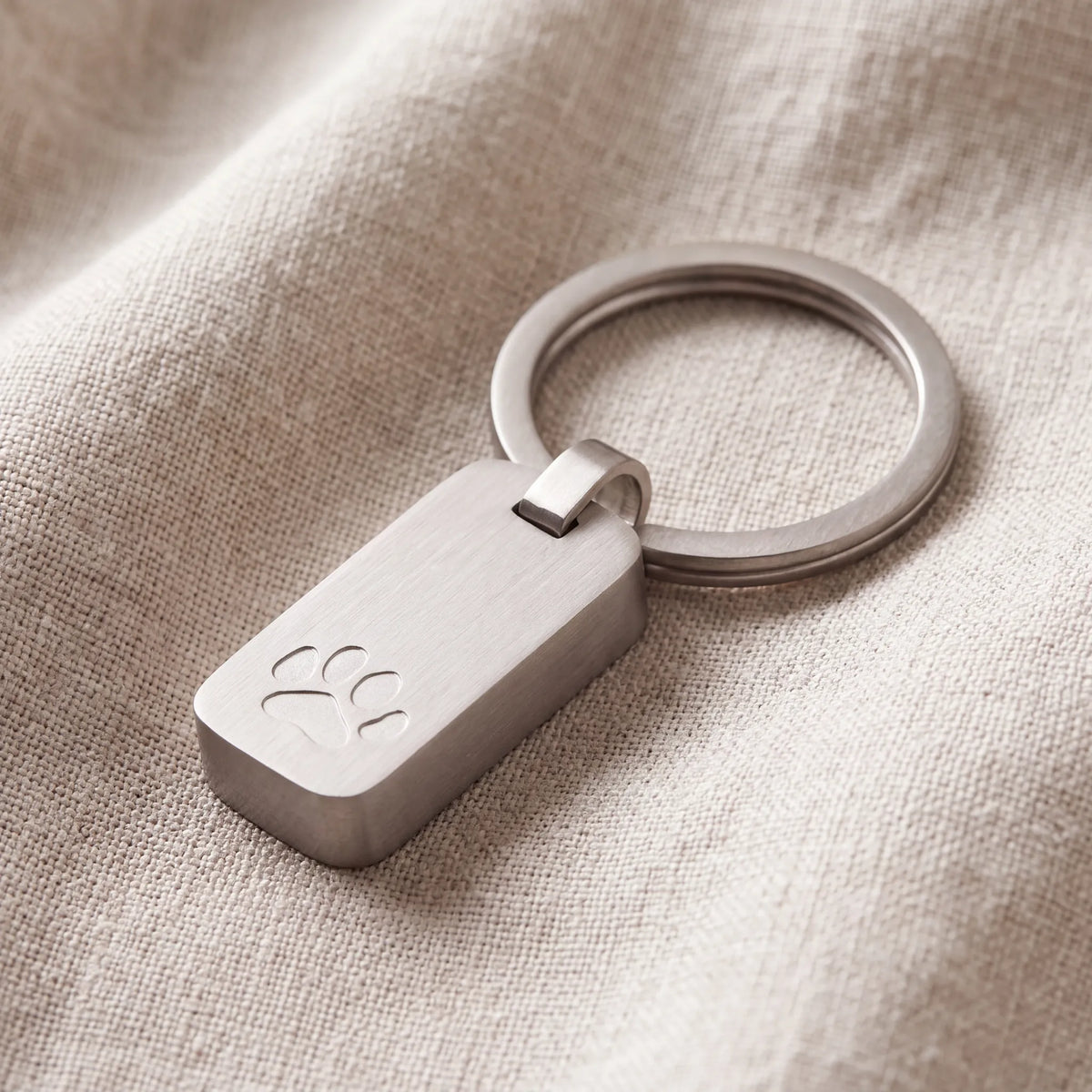 Brushed-Metal-Pawprint-Pet-Memorial-Ashes-Keyring-in-Silver-On-Linen