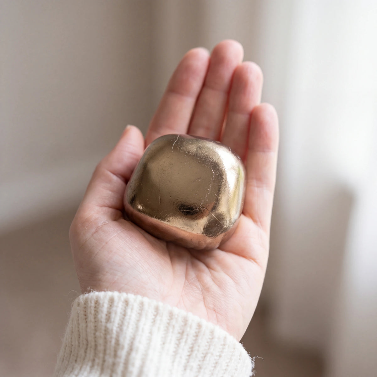 Cuddle Stone Keepsake Urn for Ashes in Gold held in the palm of a hand