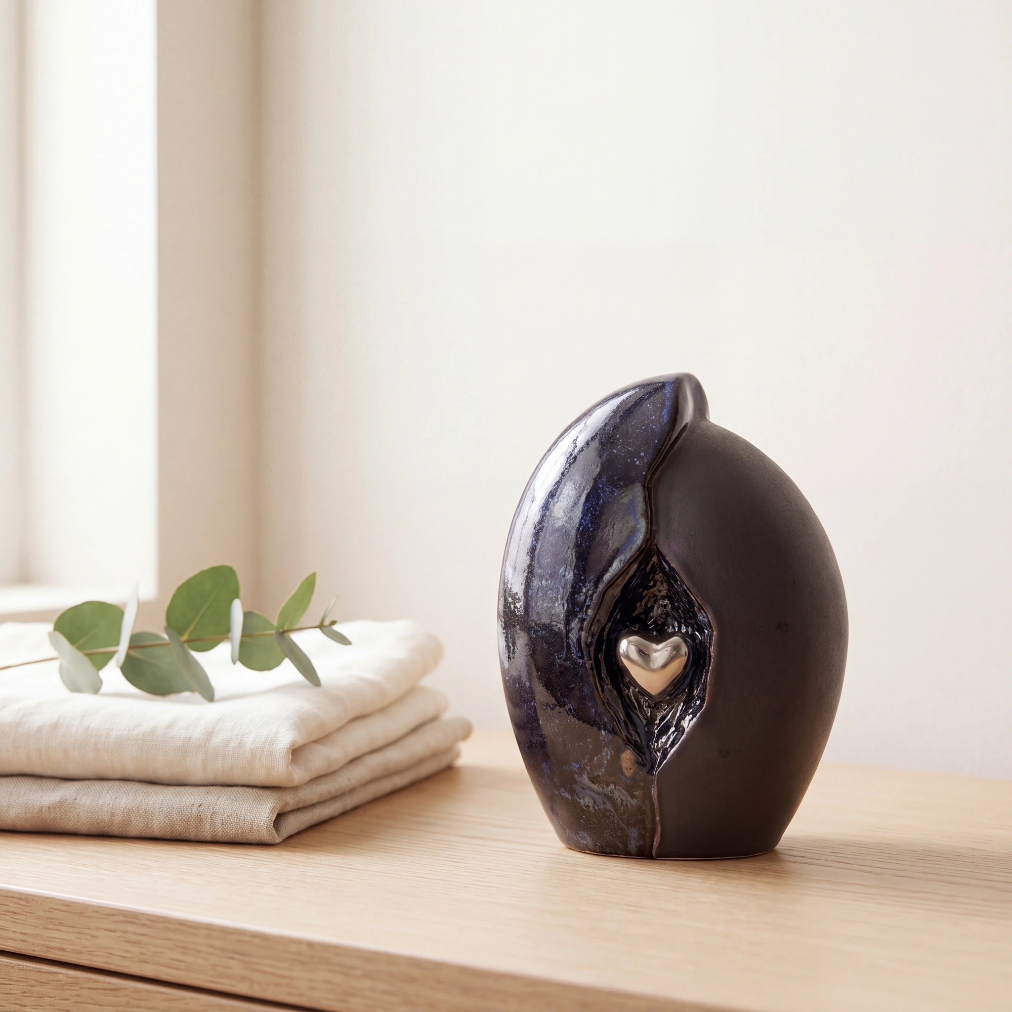 Embrace-Heart-Small-Urn-for-Ashes-in-Dark-Blue-and-Black-Folded-Linen