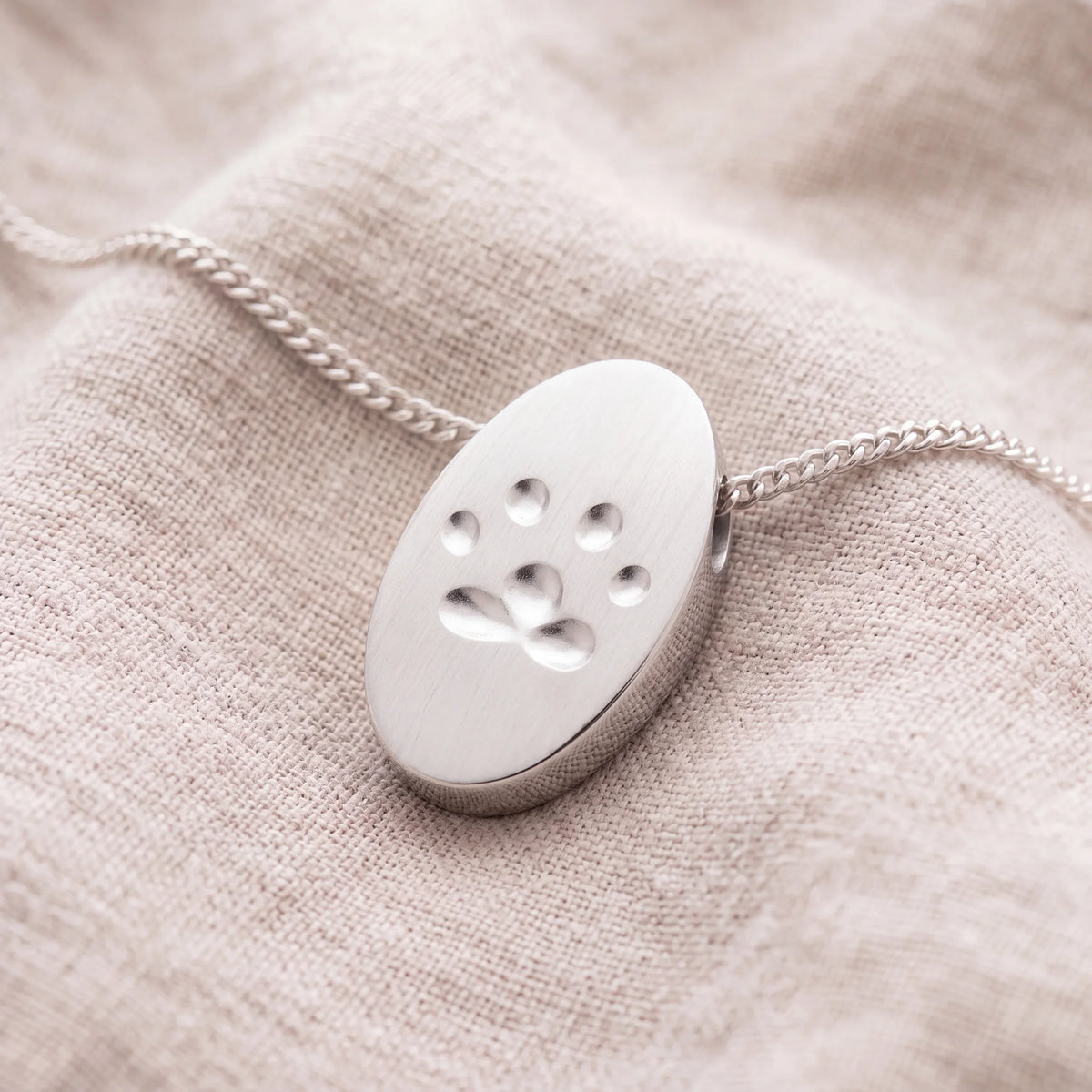 Self-fill-Paw-Print-Oval-Memorial-Ashes-Pendant-On-Linen