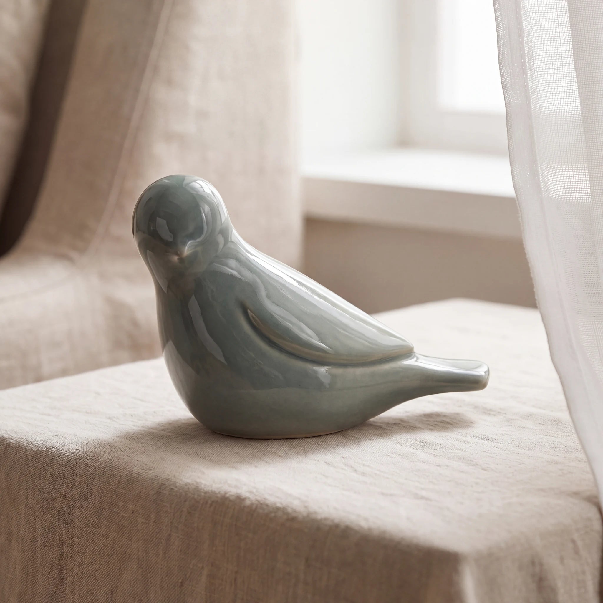 Whistling-Bird-Keepsake-Urn-for-Ashes-in-Sage-Green-Linen-Table