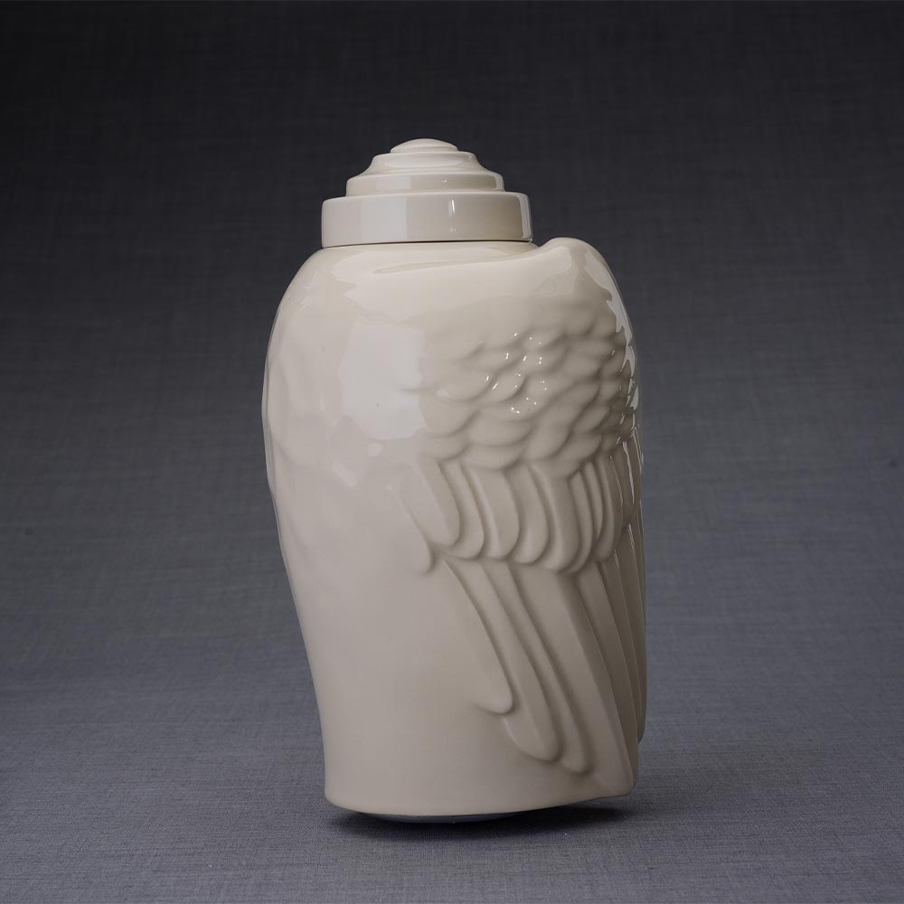 Wings Cremation Urn for Ashes in Cream Facing Right Dark Background