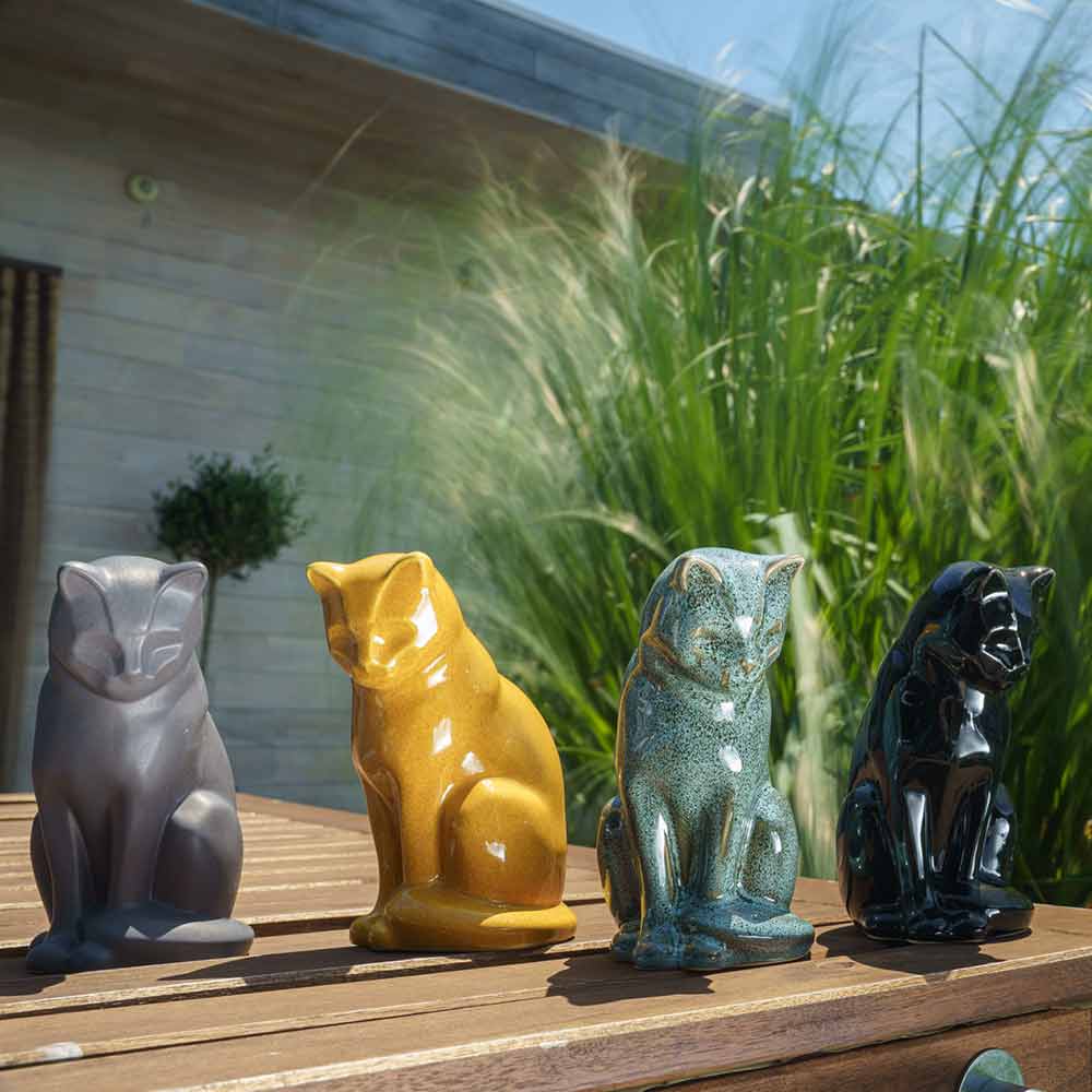 cat urns for ashes outside in sun on table glossy amber
