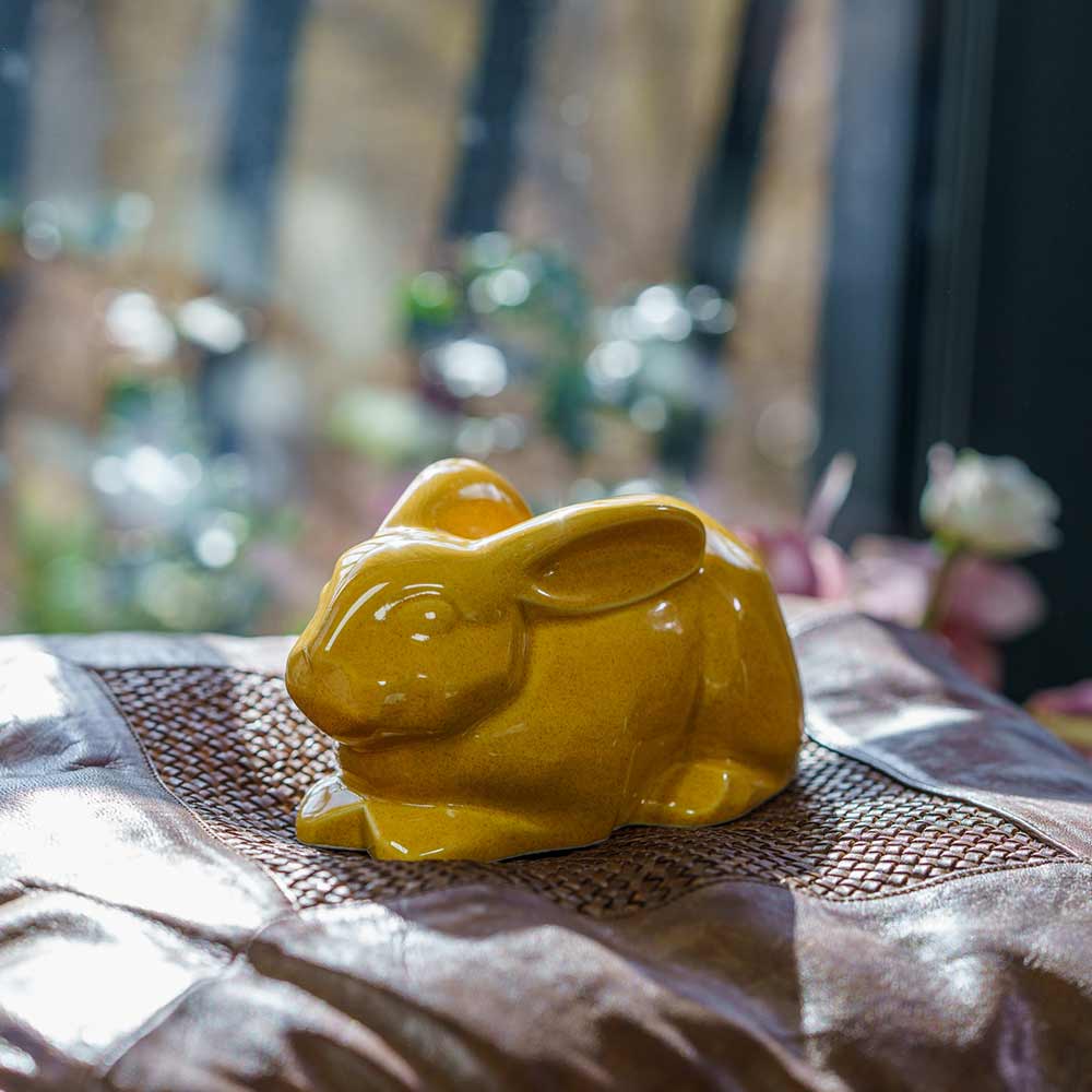 Rabbit Urn For Ashes Amber On Cushion.Left
