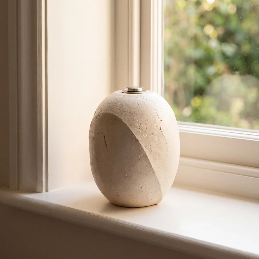 Cocoon stoneware urn for ashes on a windowsill