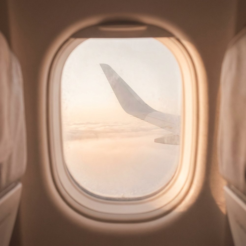 An aeroplane wing seen through the cabin window at sunrise