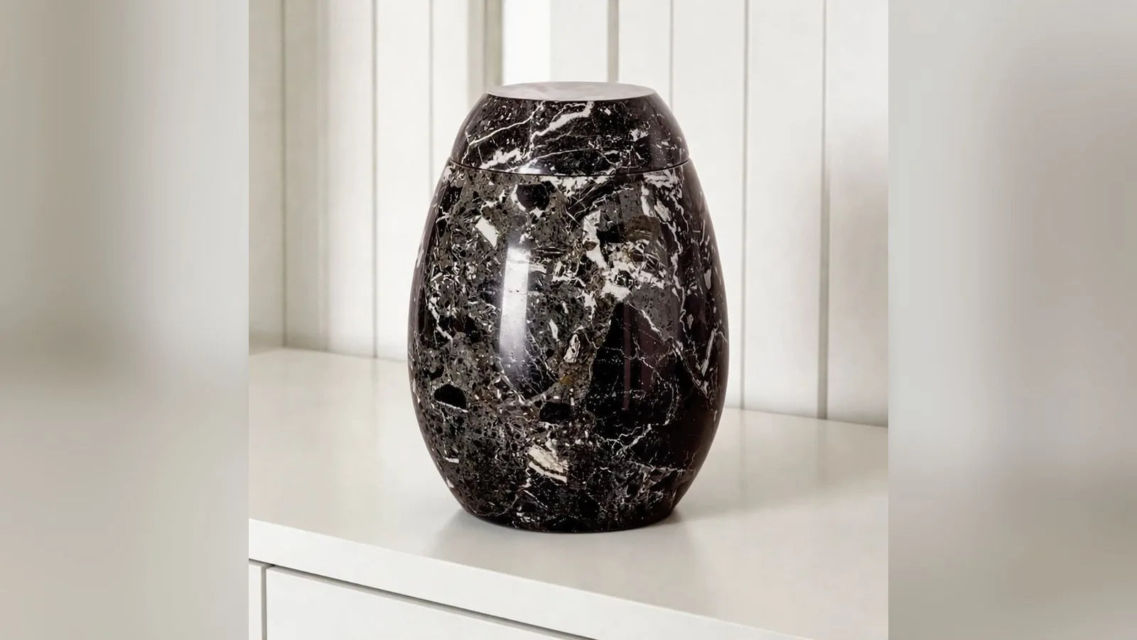 Marble adult cremation urn in black and grey in a living room