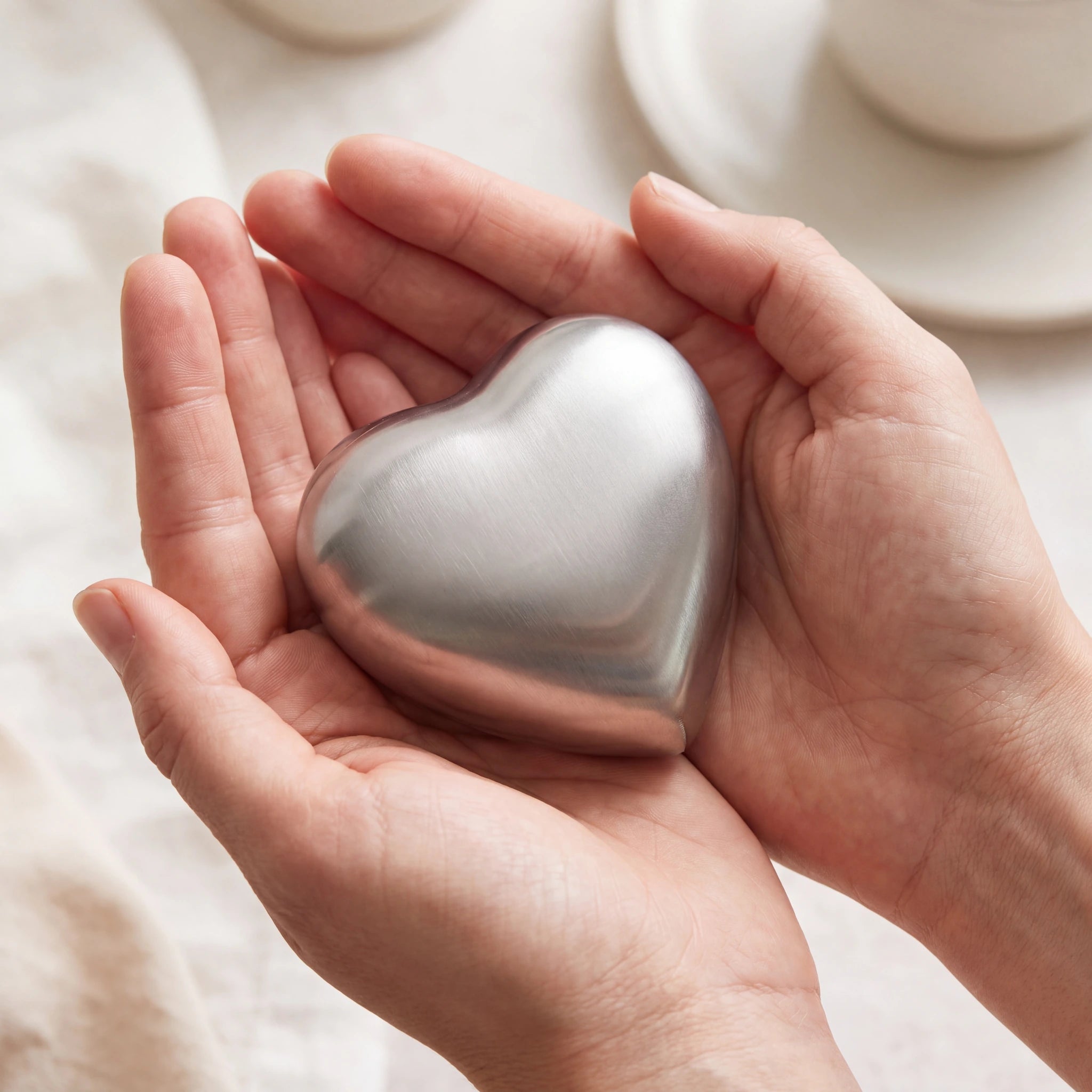 Brushed-Metal-Heart-Keepsake-Urn-for-Ashes-in-Silver-Cupped-in-Hands