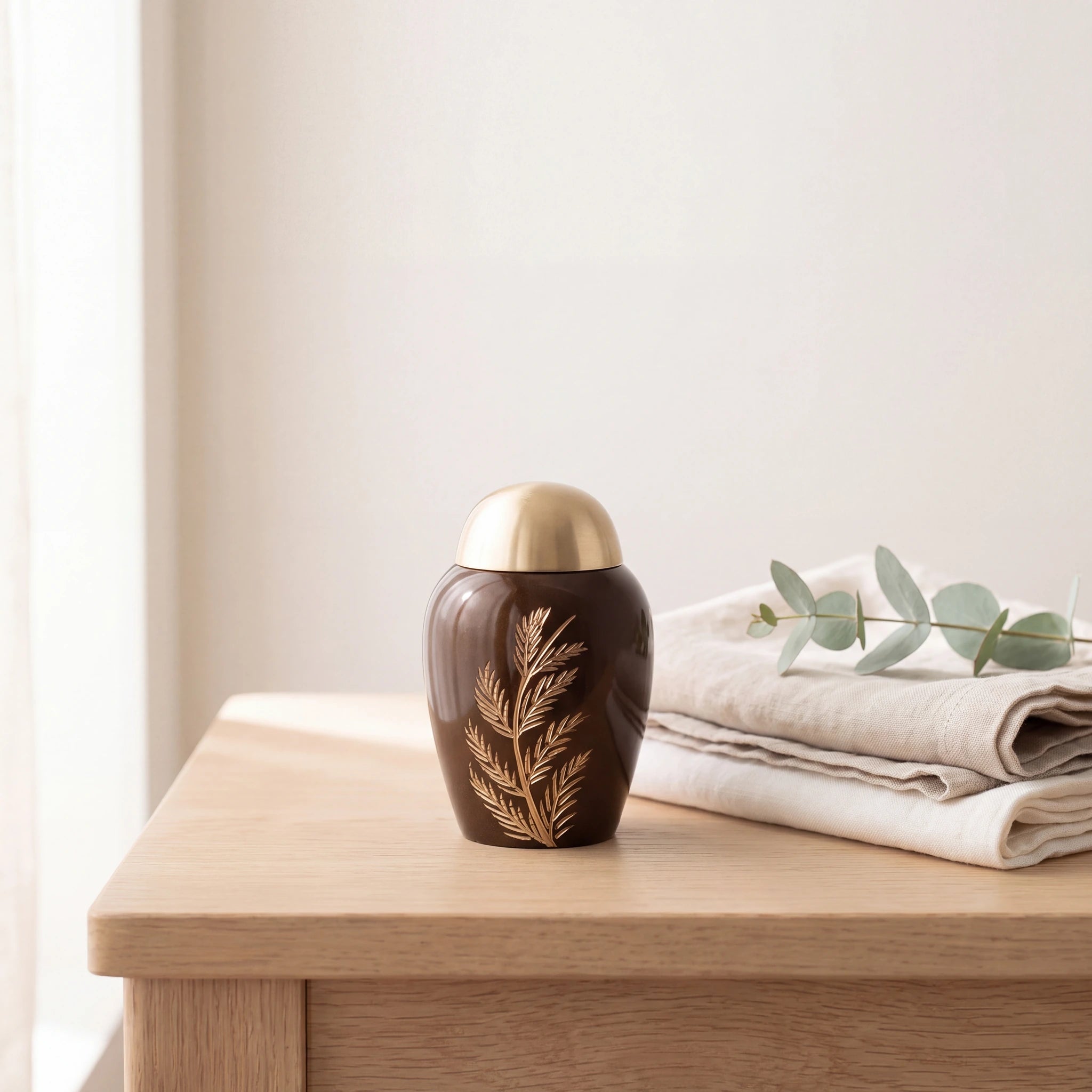 Fern-Metal-Keepsake-Urn-for-Ashes-in-Brown-and-Gold-Folded-Linen