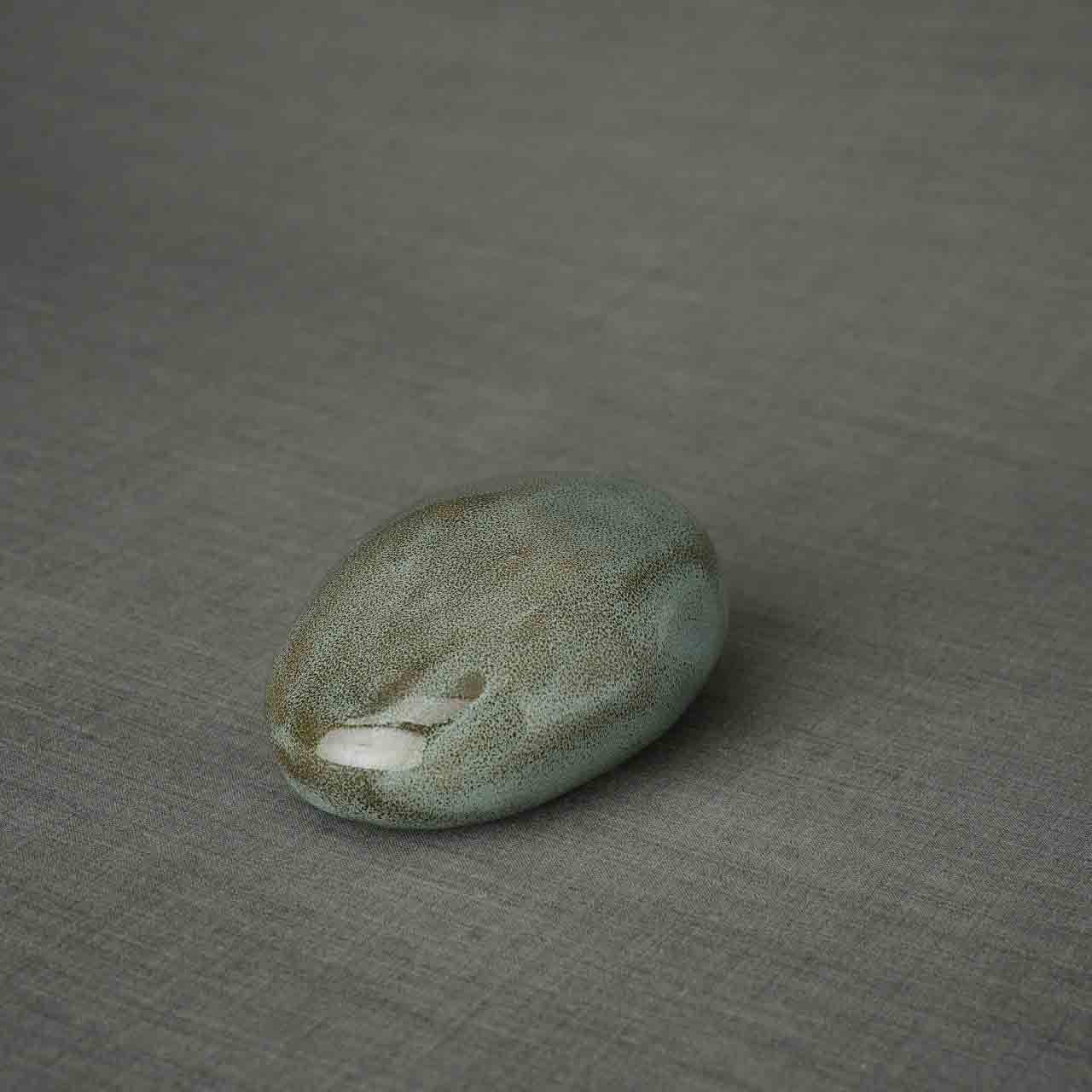 Pebbles Ashes Keepsake Urn in Oily Green Facing Left Dark Background