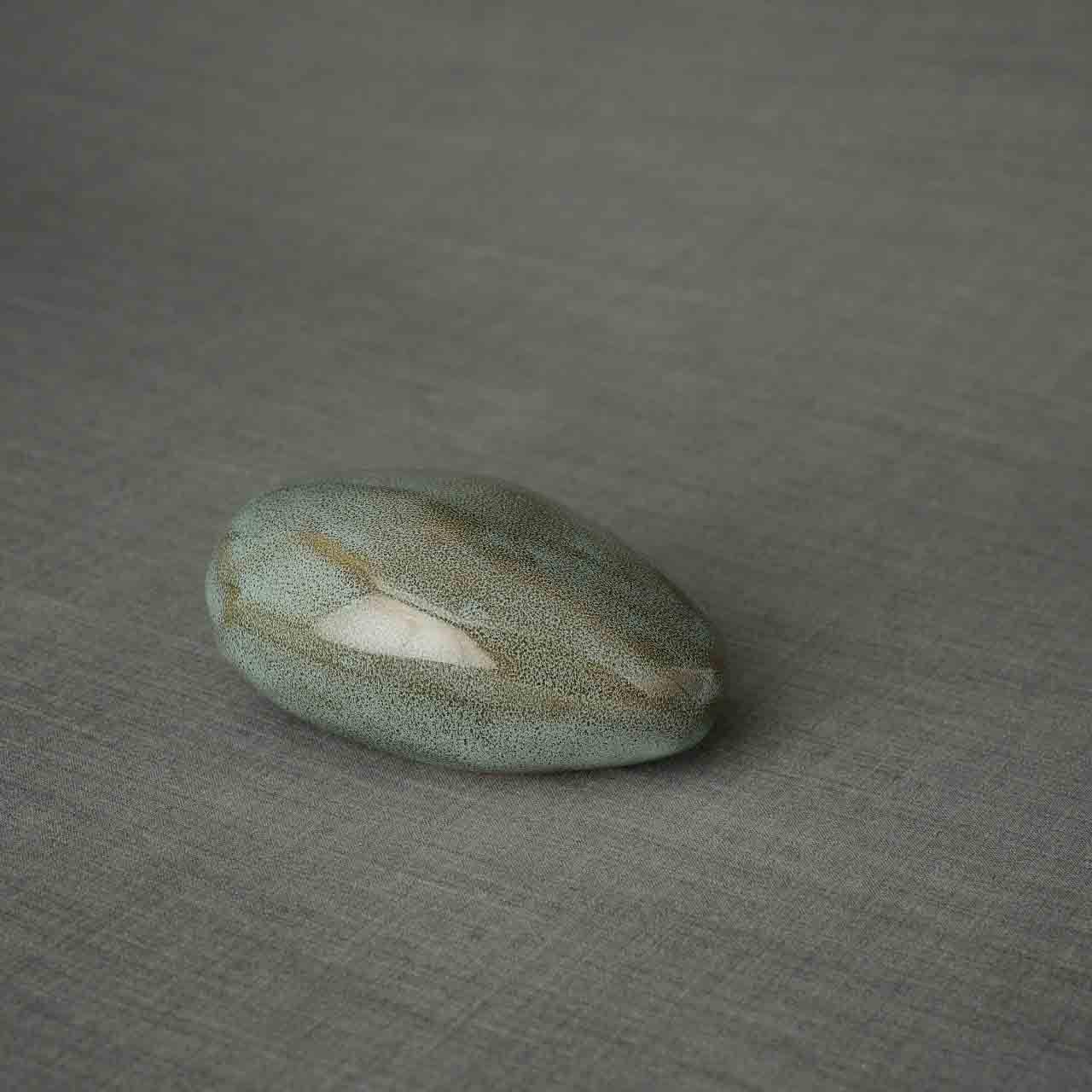 Pebbles Ashes Keepsake Urn in Oily Green Facing Right Dark Background