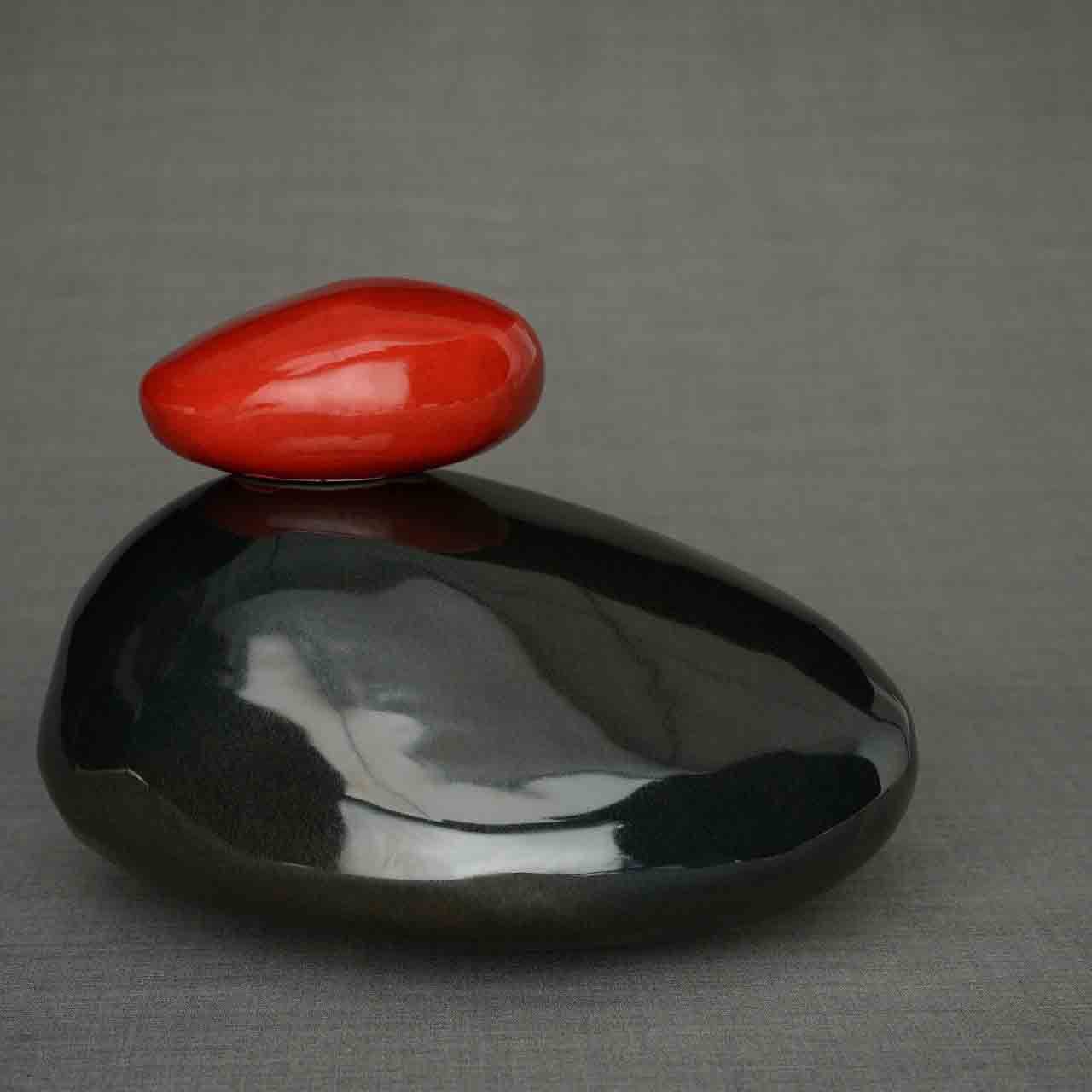 Pebbles Cremation Urn for Ashes in Glossy Black and Red Facing Left Dark Background