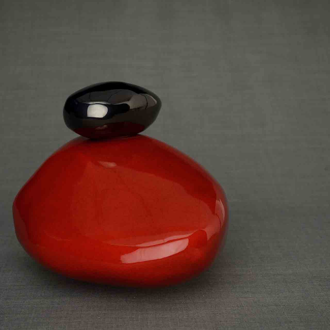 Pebbles Cremation Urn for Ashes in Red and Glossy Black Facing Left Dark Background