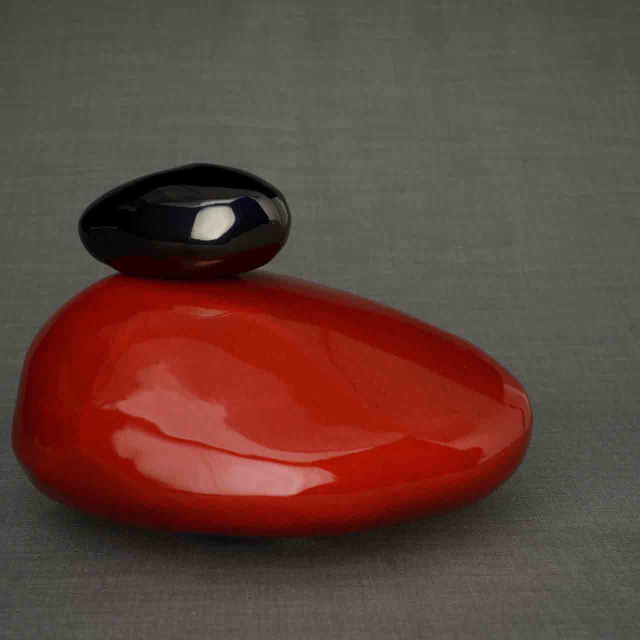 Pebbles Cremation Urn for Ashes in Red and Glossy Black Facing Right Dark Background