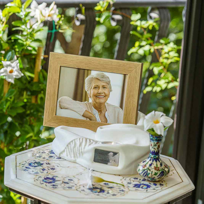 Picture Frame Pet Urns For Ashes In Matte White Ceramic Facing Left With Photo Of Female On Table