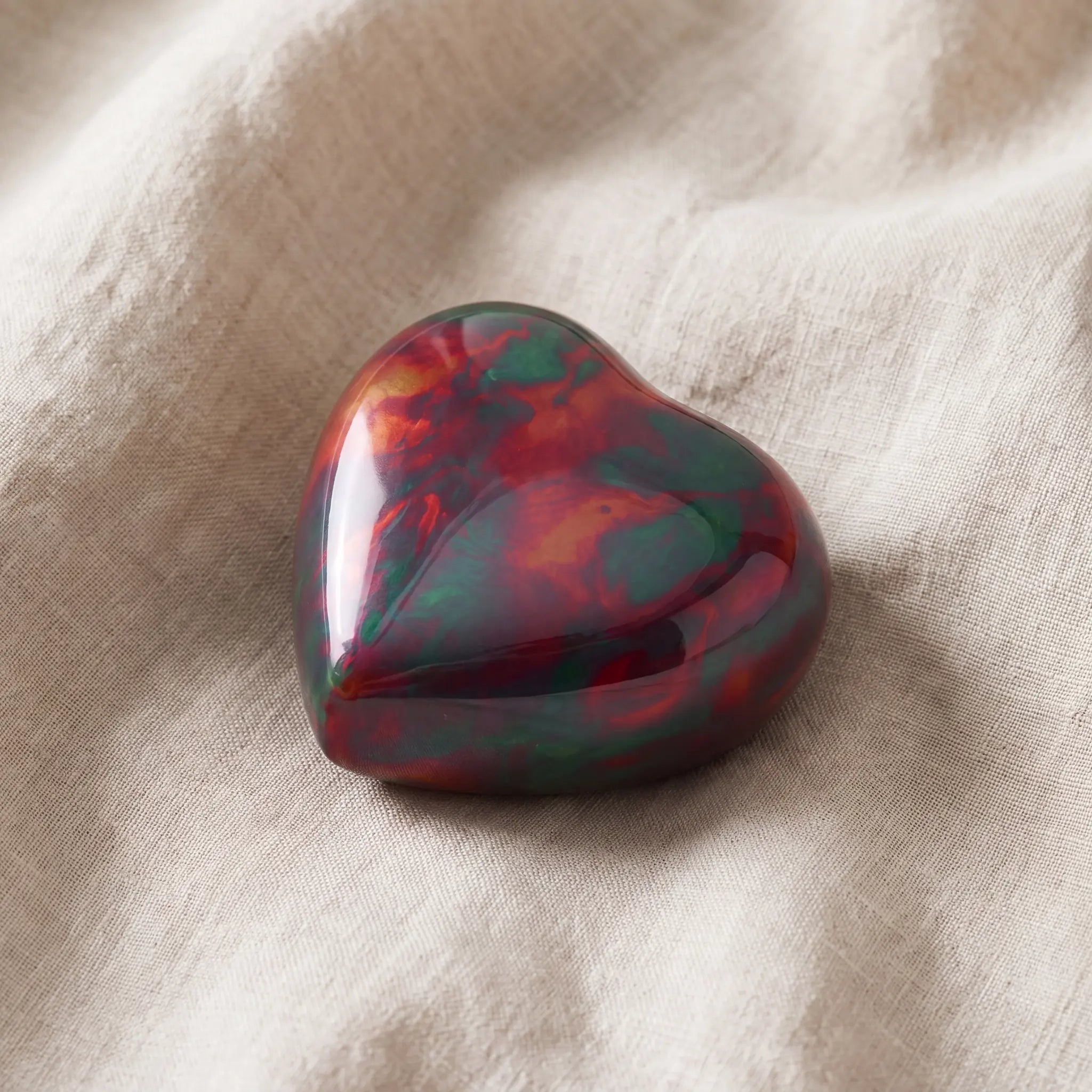 Raku-Metal-Heart-Keepsake-Urn-for-Ashes-in-Red-and-Green-On-Linen
