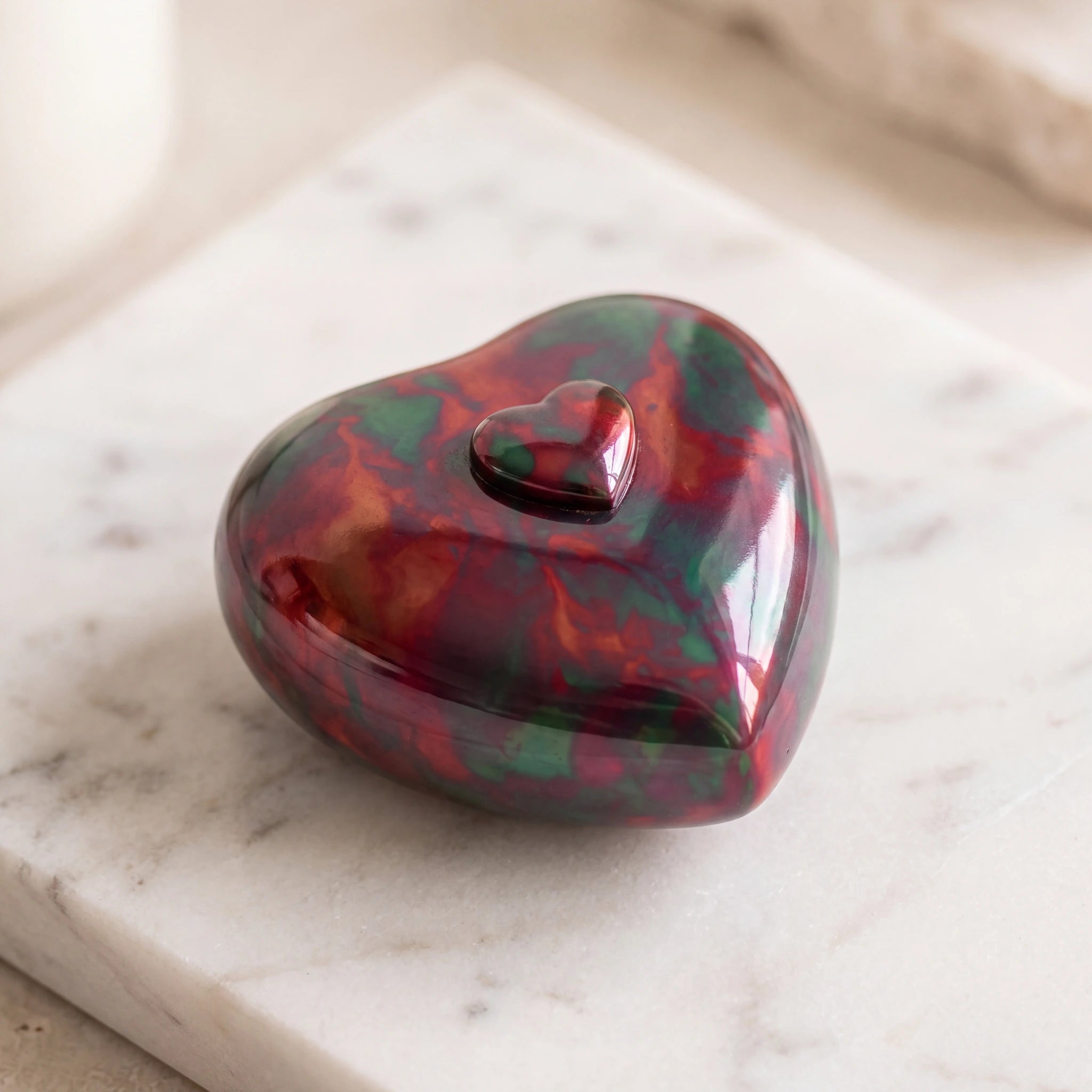 Raku-Metal-Heart-Keepsake-Urn-for-Ashes-in-Red-and-Green-On-Marble