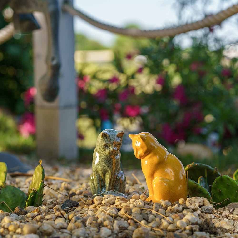 Small Cat Urns For Ashes Outside In The Sun Oily Green