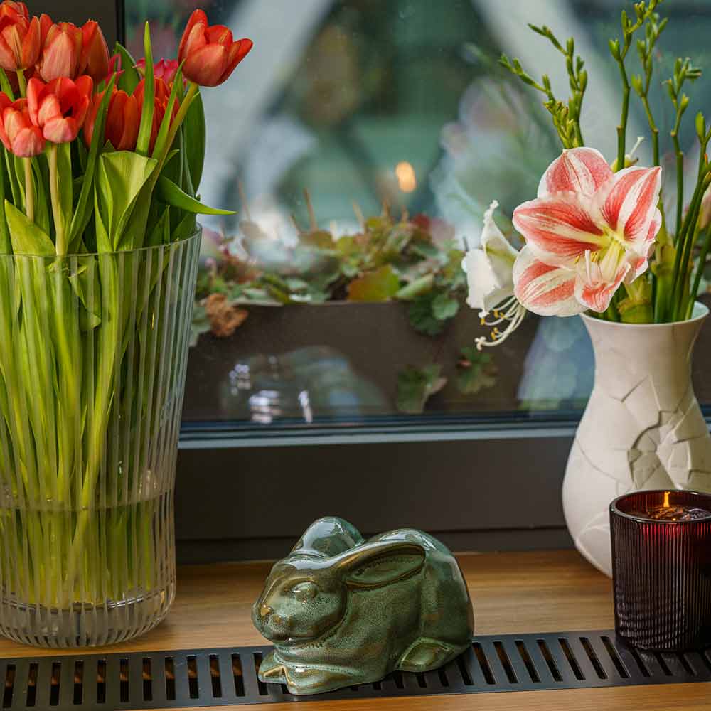 Rabbit Urn For Ashes Oily Green By Window Facing Front Left With Flowers