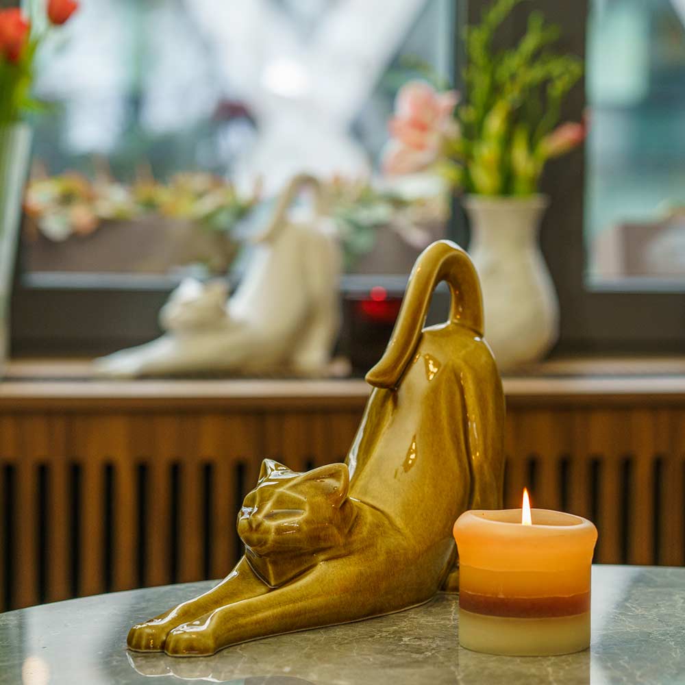 Stretching Cat Urn For Ashes Dark Sand On Table Front Left With Candle