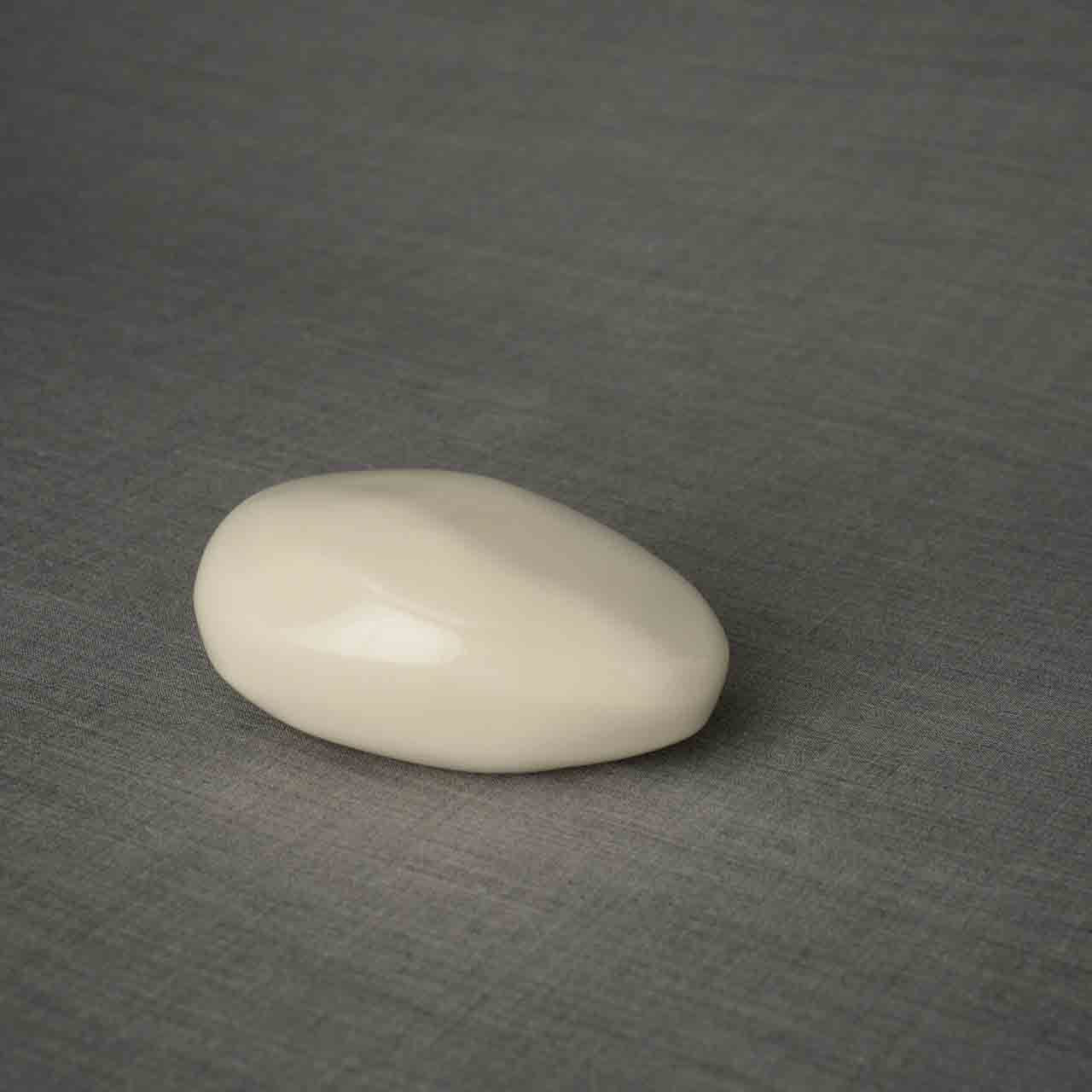 Pebbles Ashes Keepsake Urn in Cream Facing Right Dark Background