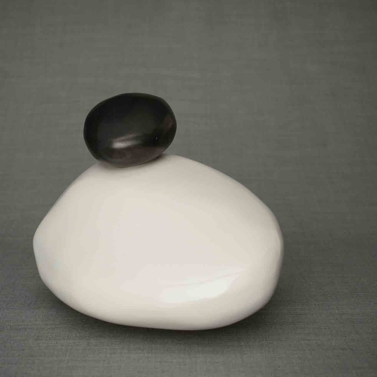 Pebbles Cremation Urn for Ashes in White and Matte Black Facing Left Dark Background
