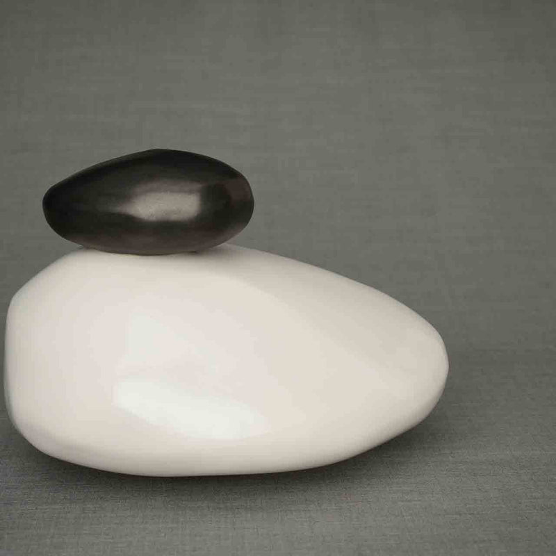 Pebbles Cremation Urn for Ashes in White and Matte Black Facing Right Dark Background