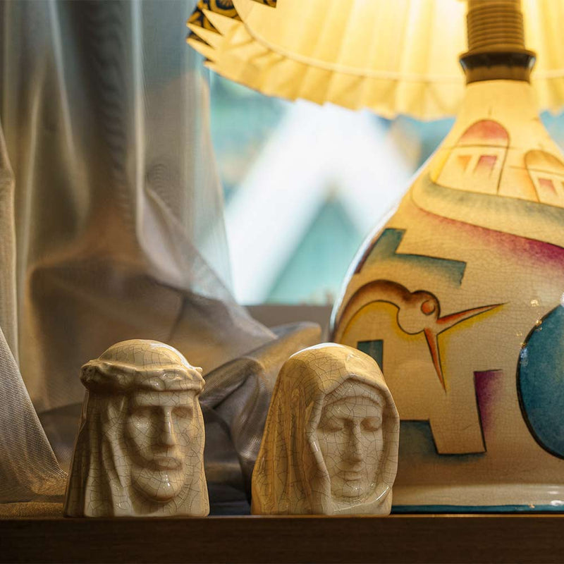 The Holy Mother Ashes Keepsake Urn with The Christ Ashes Keepsake Crackle Glaze on Table by Lamp